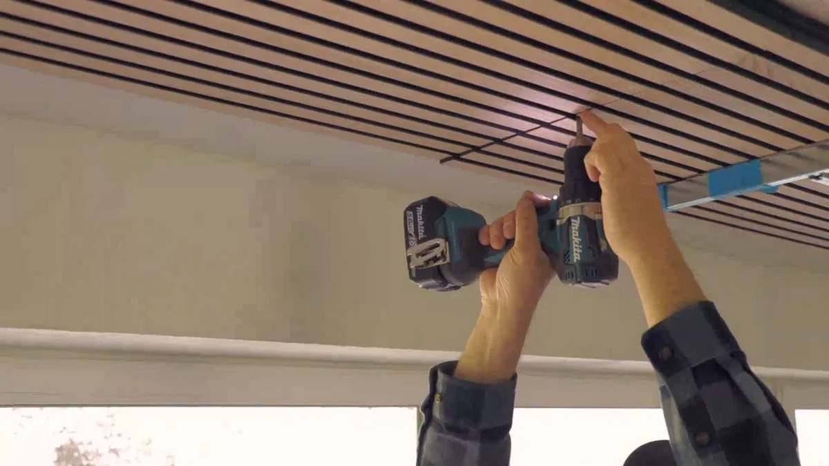 Fixing acoustic ceiling panels with screws for stable and long-lasting soundproofing.