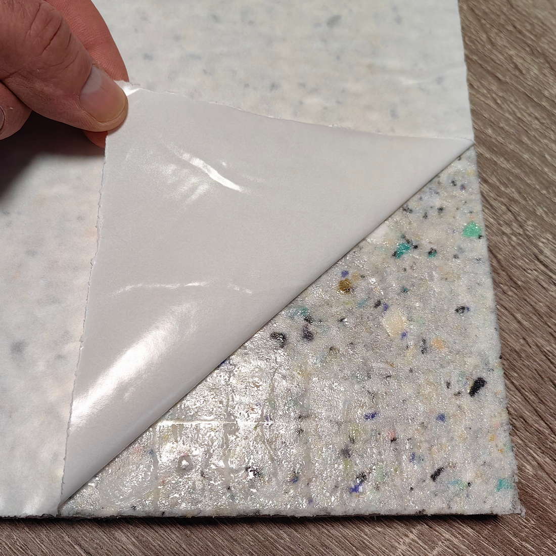 Close-up of self-adhesive backing on a soundproofing panel for ceiling installation.