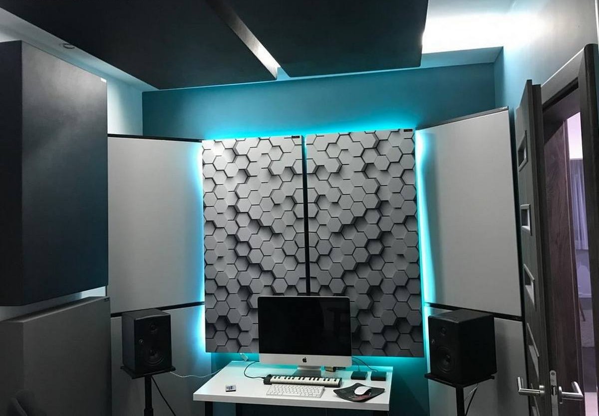 Figured acoustic diffuser panels behind a computer desk in a small home studio.