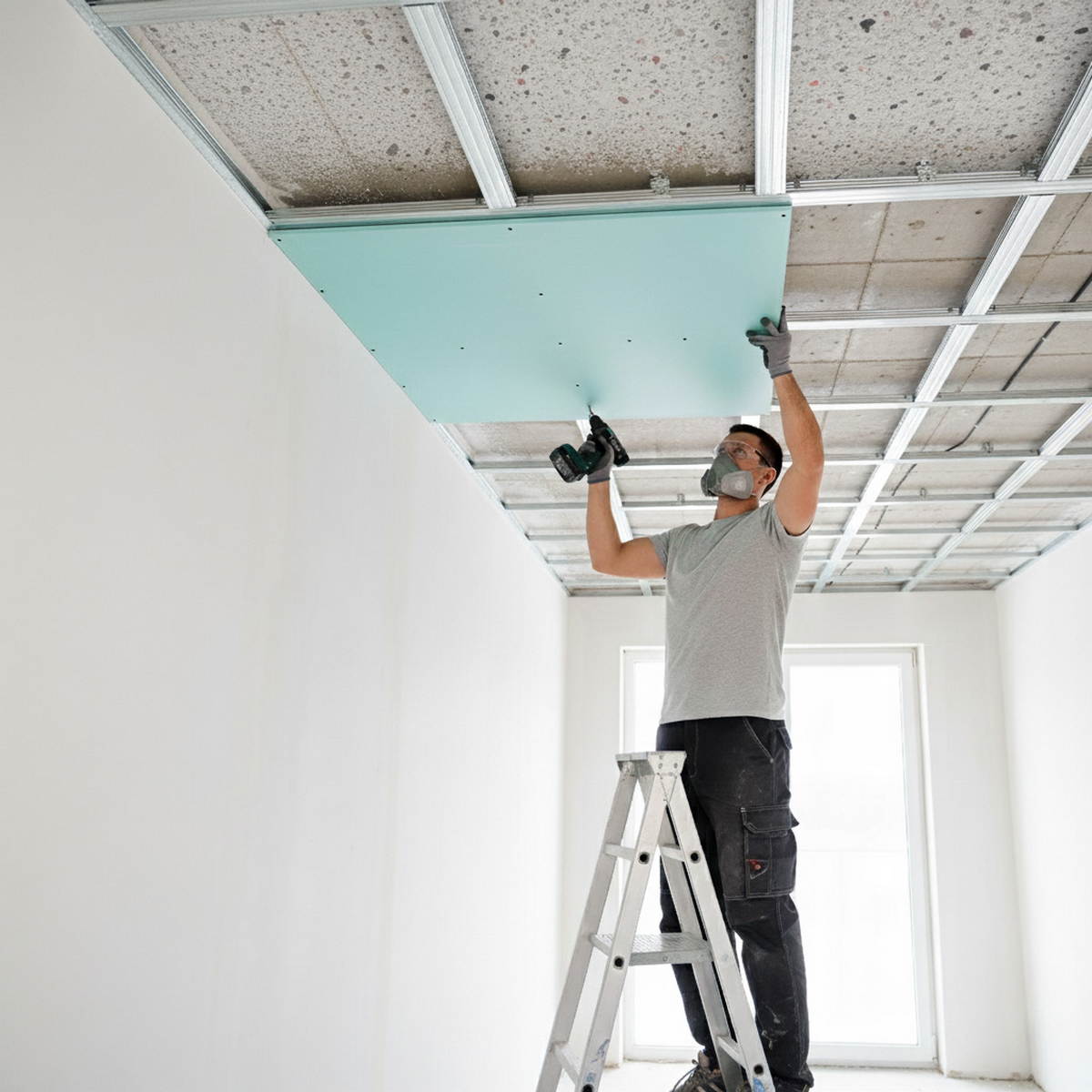 Worker installing suspended ceiling panels with sound insulation